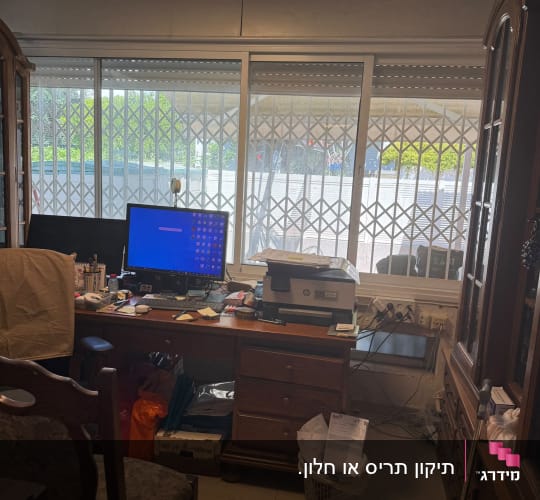 משרד עם שולחן מחשב וחלון עם תריסים